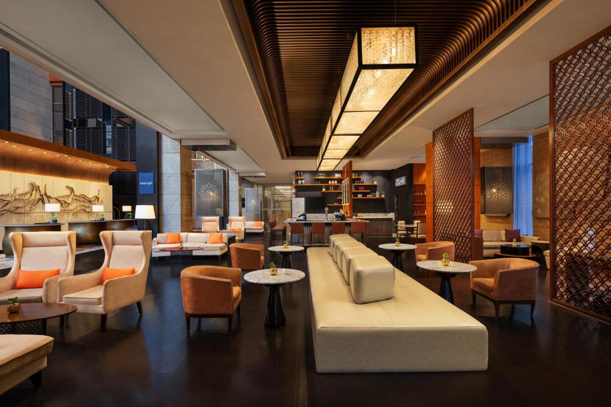 a restaurant with tables and chairs and a lobby at Sheraton Hyderabad Hotel in Hyderabad