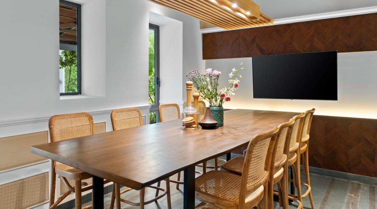 a dining room with a wooden table and chairs at The Astor - All Suites Hotel Candolim Goa in Candolim a dining room with a wooden table and chairs at The Astor - All Suites Hotel Candolim Goa in Candolim