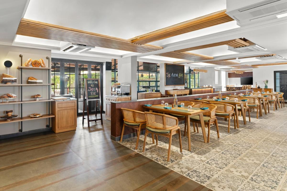 a restaurant with a bar with tables and chairs at The Astor - All Suites Hotel Candolim Goa in Candolim a restaurant with a bar with tables and chairs at The Astor - All Suites Hotel Candolim Goa in Candolim