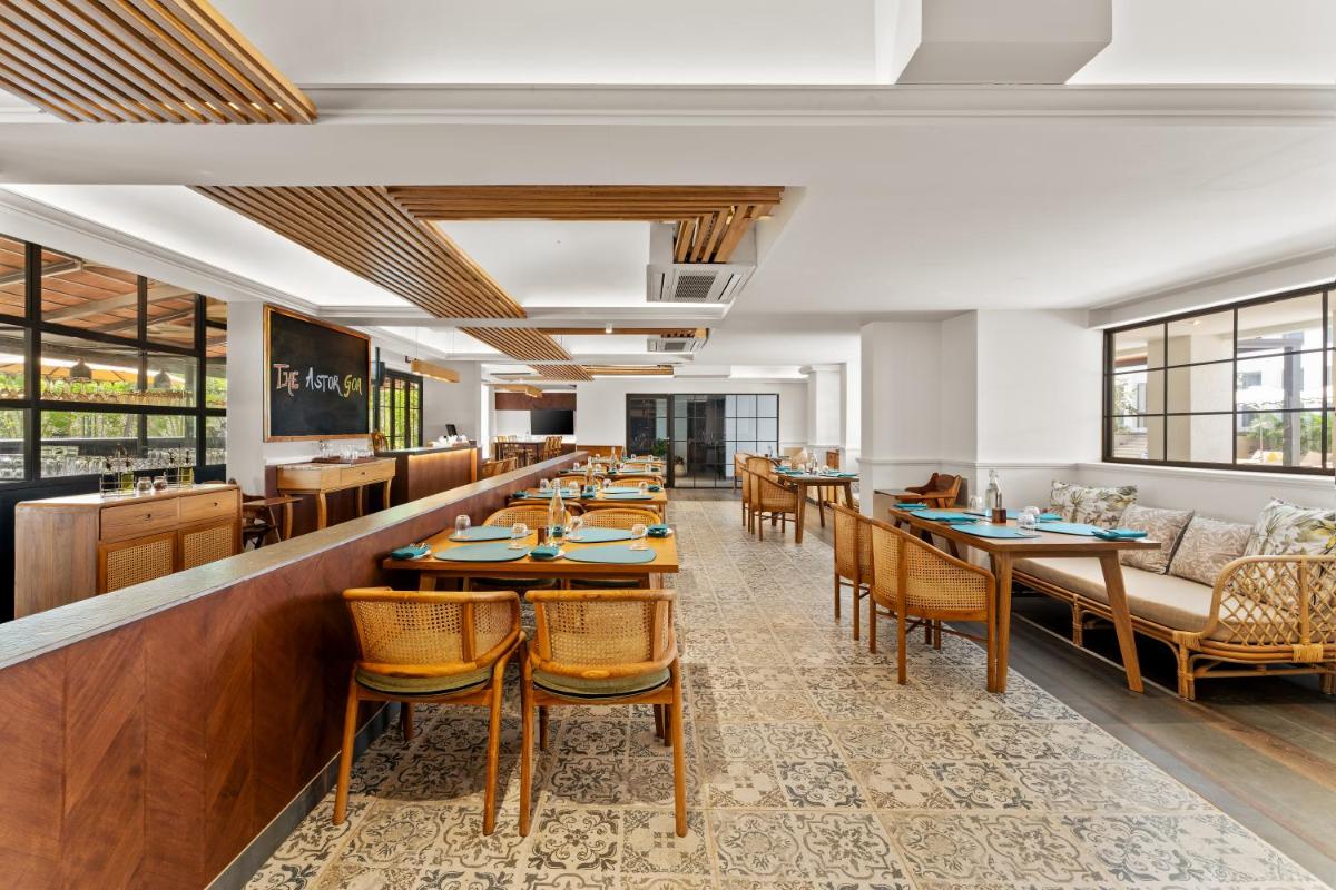 a restaurant with tables and chairs and a bar at The Astor - All Suites Hotel Candolim Goa in Candolim a restaurant with tables and chairs and a bar at The Astor - All Suites Hotel Candolim Goa in Candolim