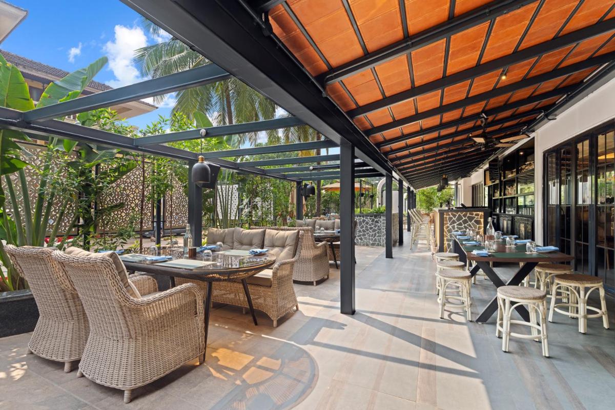 an outdoor patio with tables and chairs and windows at The Astor - All Suites Hotel Candolim Goa in Candolim an outdoor patio with tables and chairs and windows at The Astor - All Suites Hotel Candolim Goa in Candolim