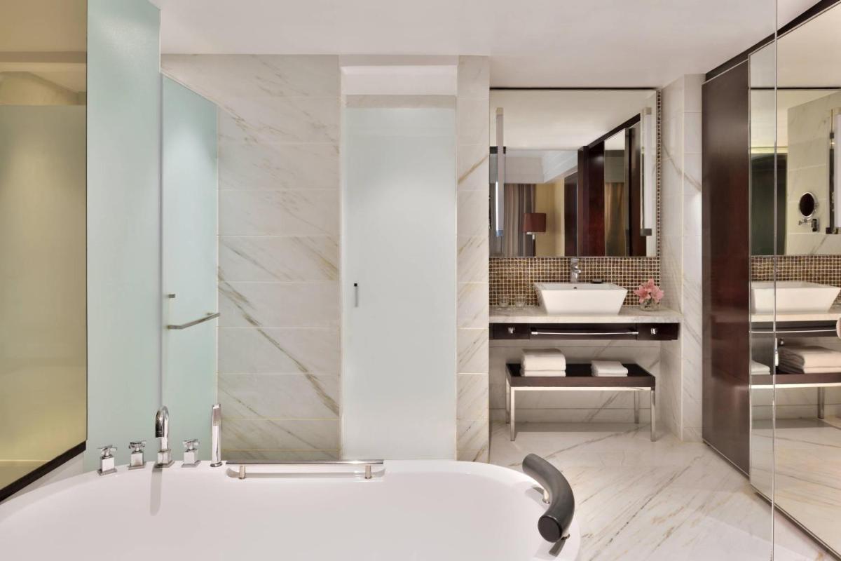 a bathroom with a tub and a sink at Jaipur Marriott Hotel in Jaipur a bathroom with a tub and a sink at Jaipur Marriott Hotel in Jaipur