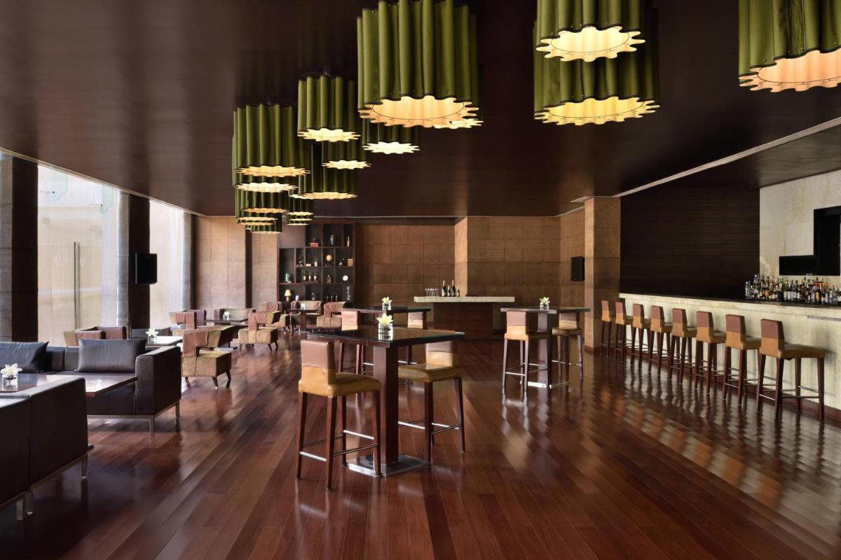 a restaurant with tables and chairs and chandeliers at Jaipur Marriott Hotel in Jaipur a restaurant with tables and chairs and chandeliers at Jaipur Marriott Hotel in Jaipur