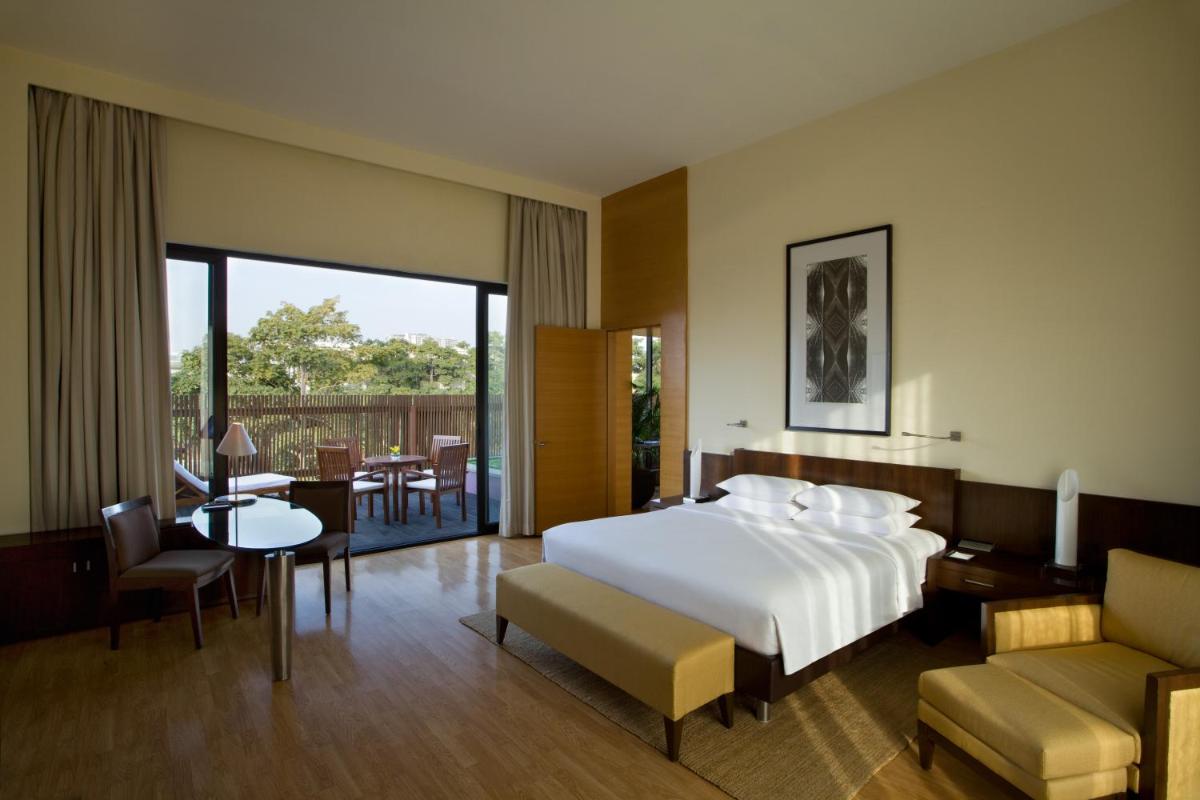 a hotel room with a bed and a table and chairs at Hyatt Hyderabad Gachibowli in Hyderabad