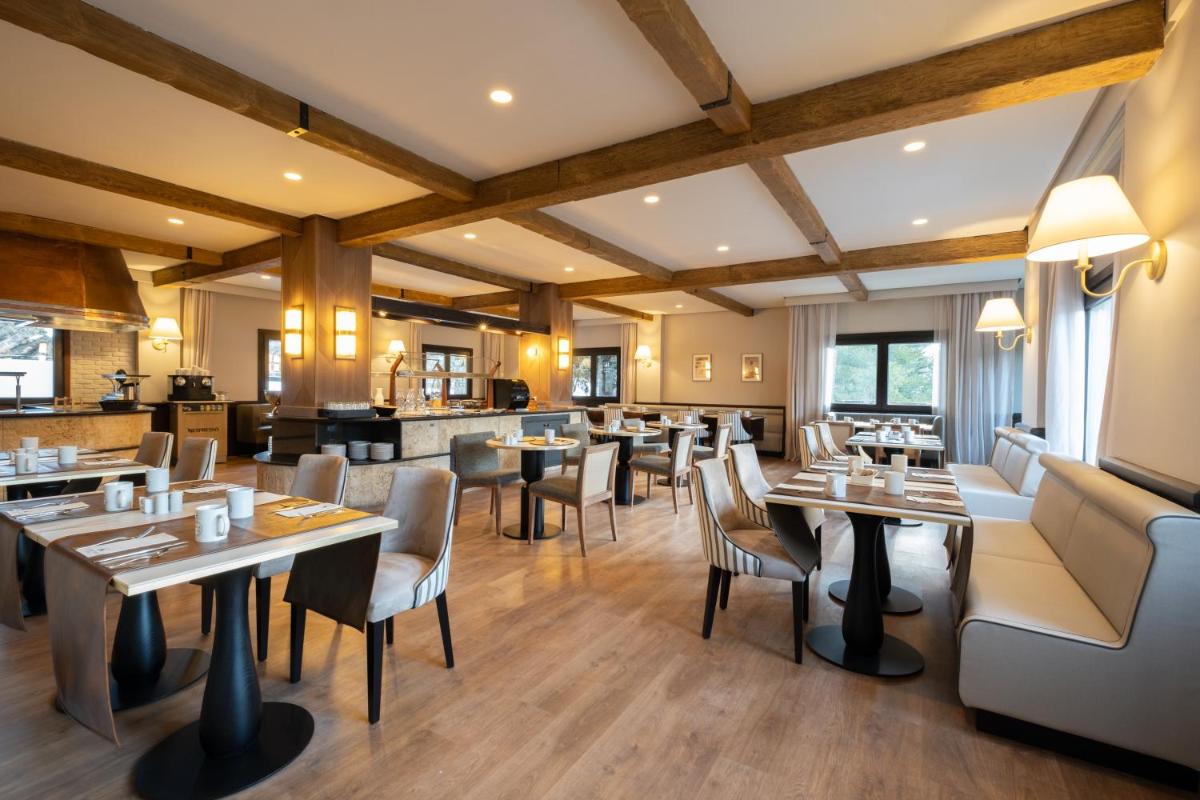 Un restaurante con suelos de madera, mesas y sillas. en Eurostars Royal Tanau, en Baqueira Beret