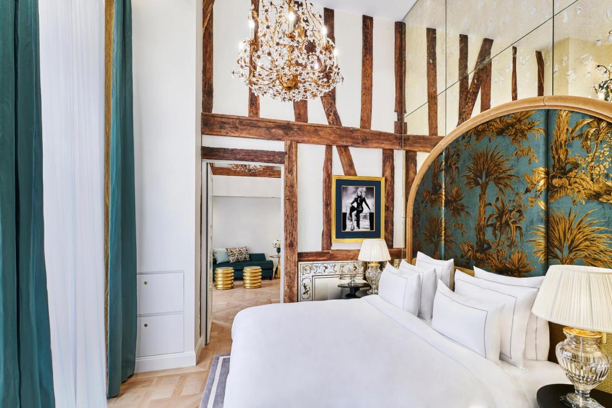 - une chambre avec un grand lit blanc et un lustre dans l'établissement Maison Barrière Vendôme, à Paris