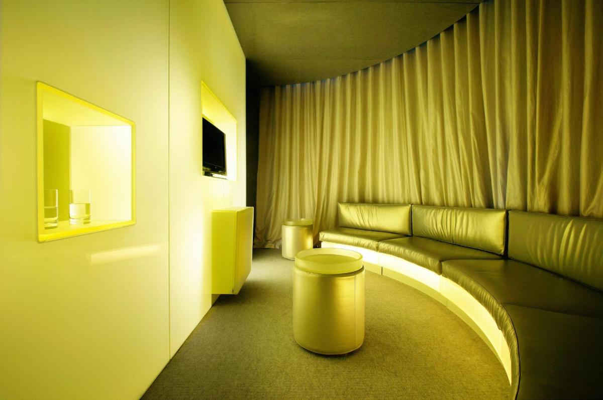 una sala de estar con un sofá y un taburete en Hotel Puerta America, en Madrid