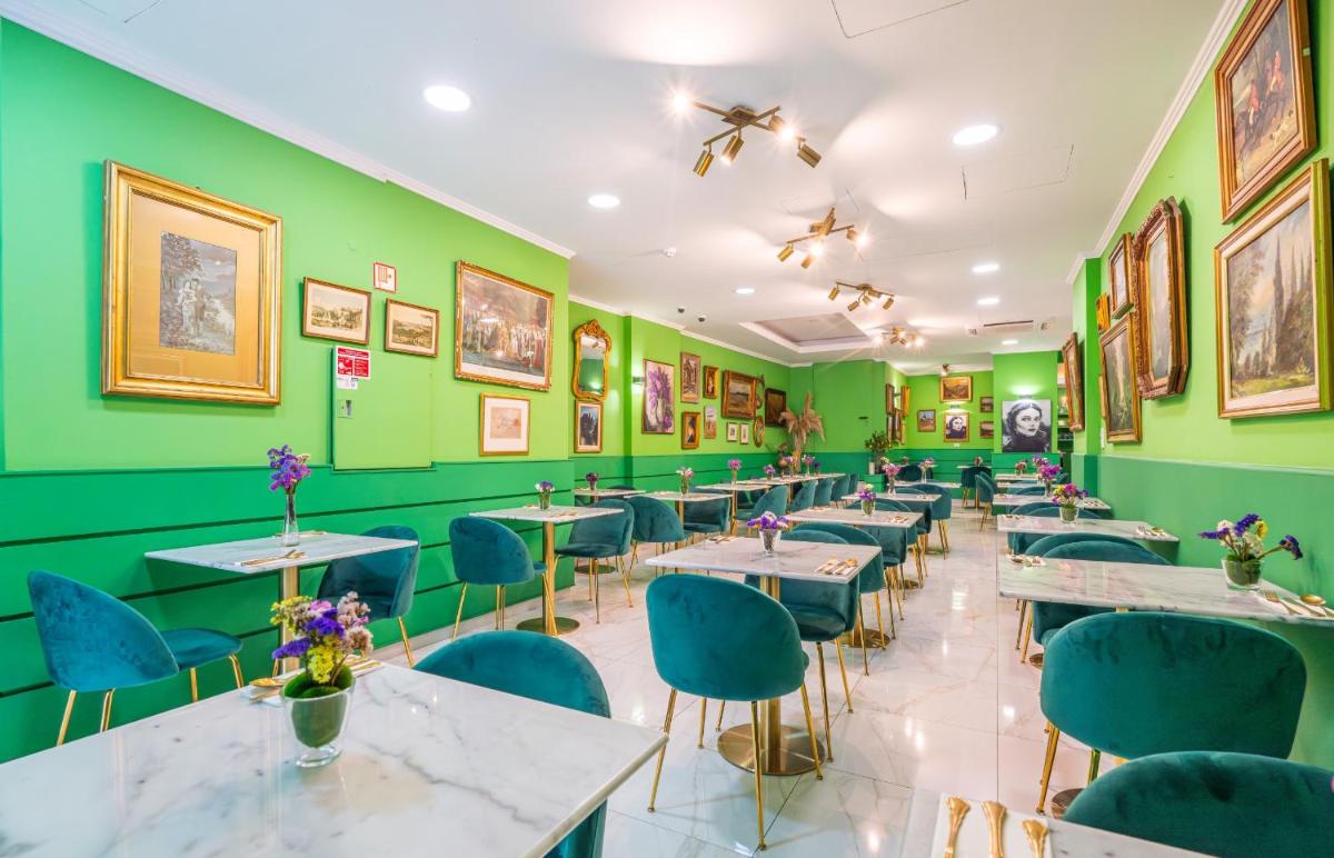 um restaurante com paredes e mesas verdes e cadeiras azuis em Sé Boutique Hotel no Funchal
