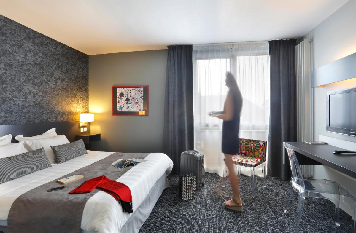 une femme debout devant une fenêtre dans une chambre d'hôtel dans l'établissement Altos Hotel & Spa, à Avranches