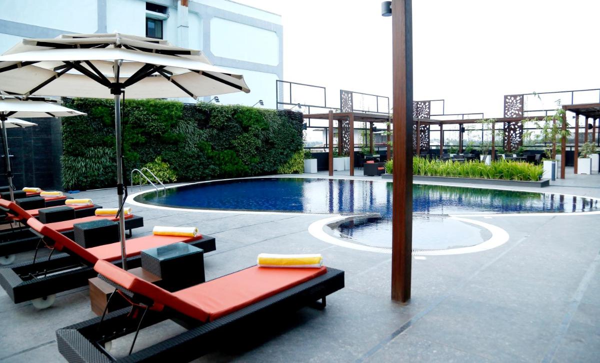 a swimming pool with a table and an umbrella at The Raviz Calicut in Kozhikode