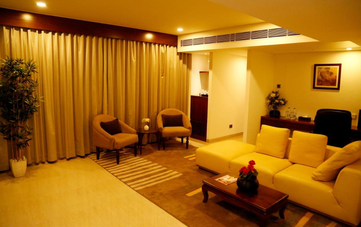 a living room with a yellow couch and chairs at The Raviz Calicut in Kozhikode