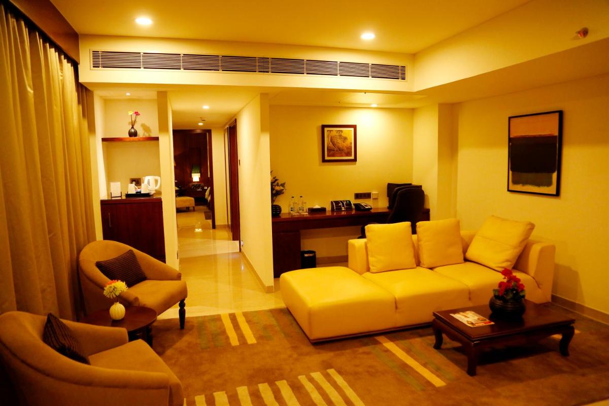 a living room with a yellow couch and chairs at The Raviz Calicut in Kozhikode