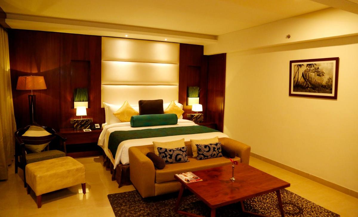 a hotel room with a bed and a couch and a table at The Raviz Calicut in Kozhikode