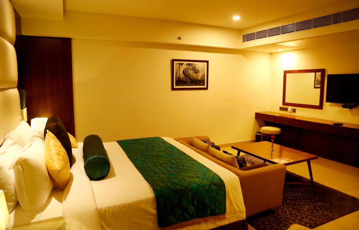 a hotel room with a large bed and a table at The Raviz Calicut in Kozhikode