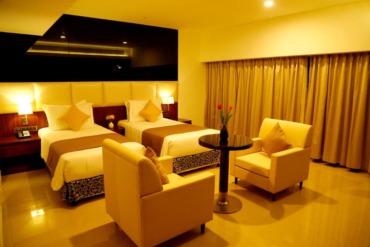 a hotel room with two beds and a table and chairs at The Raviz Calicut in Kozhikode