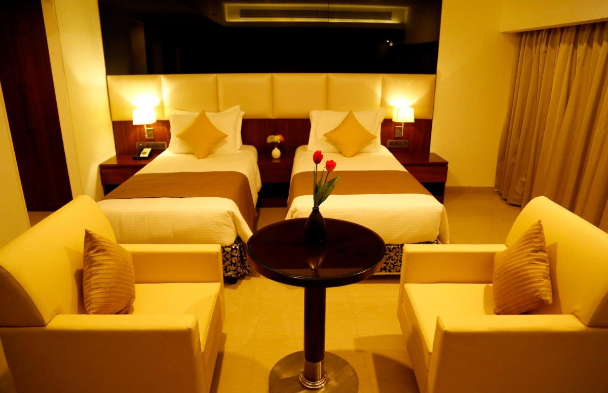 a hotel room with two beds and a table and chairs at The Raviz Calicut in Kozhikode