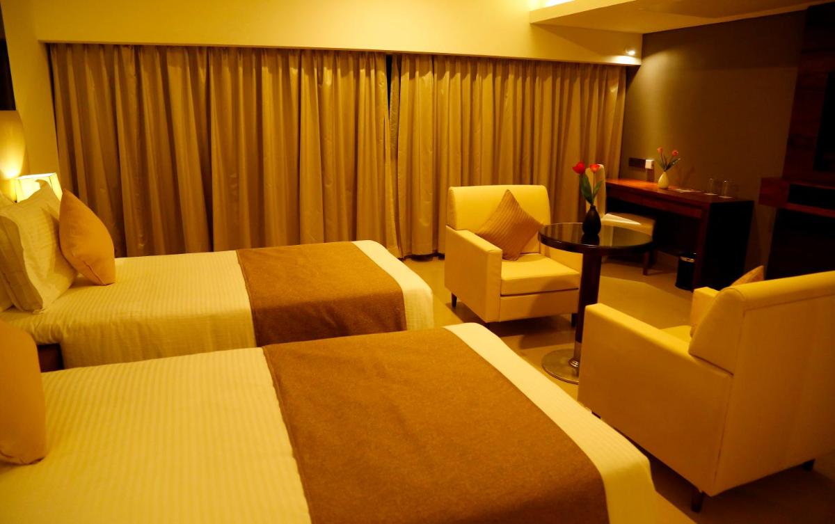 a hotel room with two beds and a desk and chair at The Raviz Calicut in Kozhikode