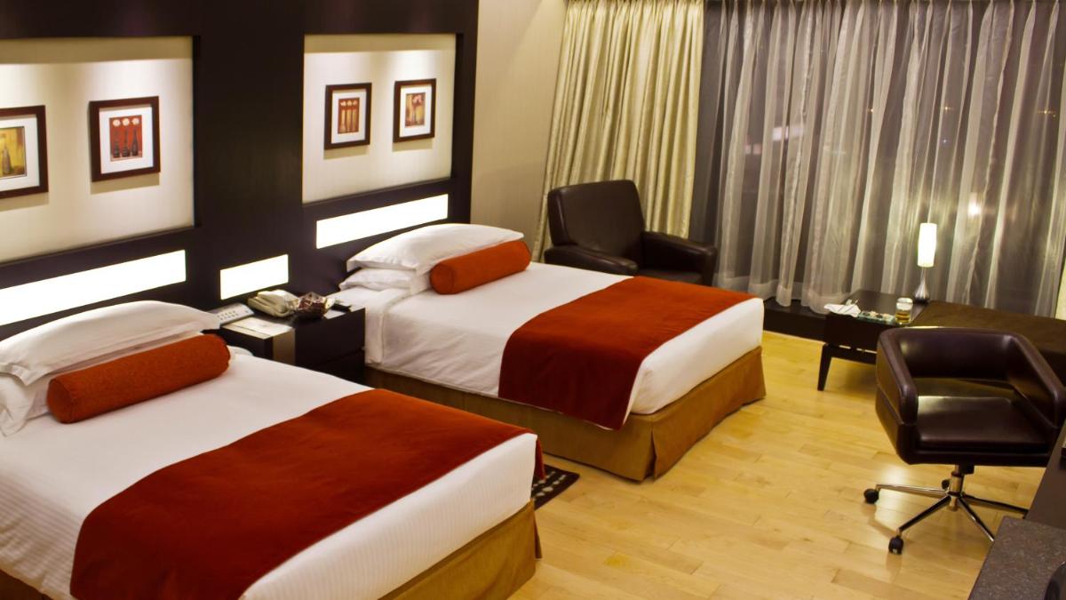 a hotel room with two beds and a desk at The Oterra in Bengaluru