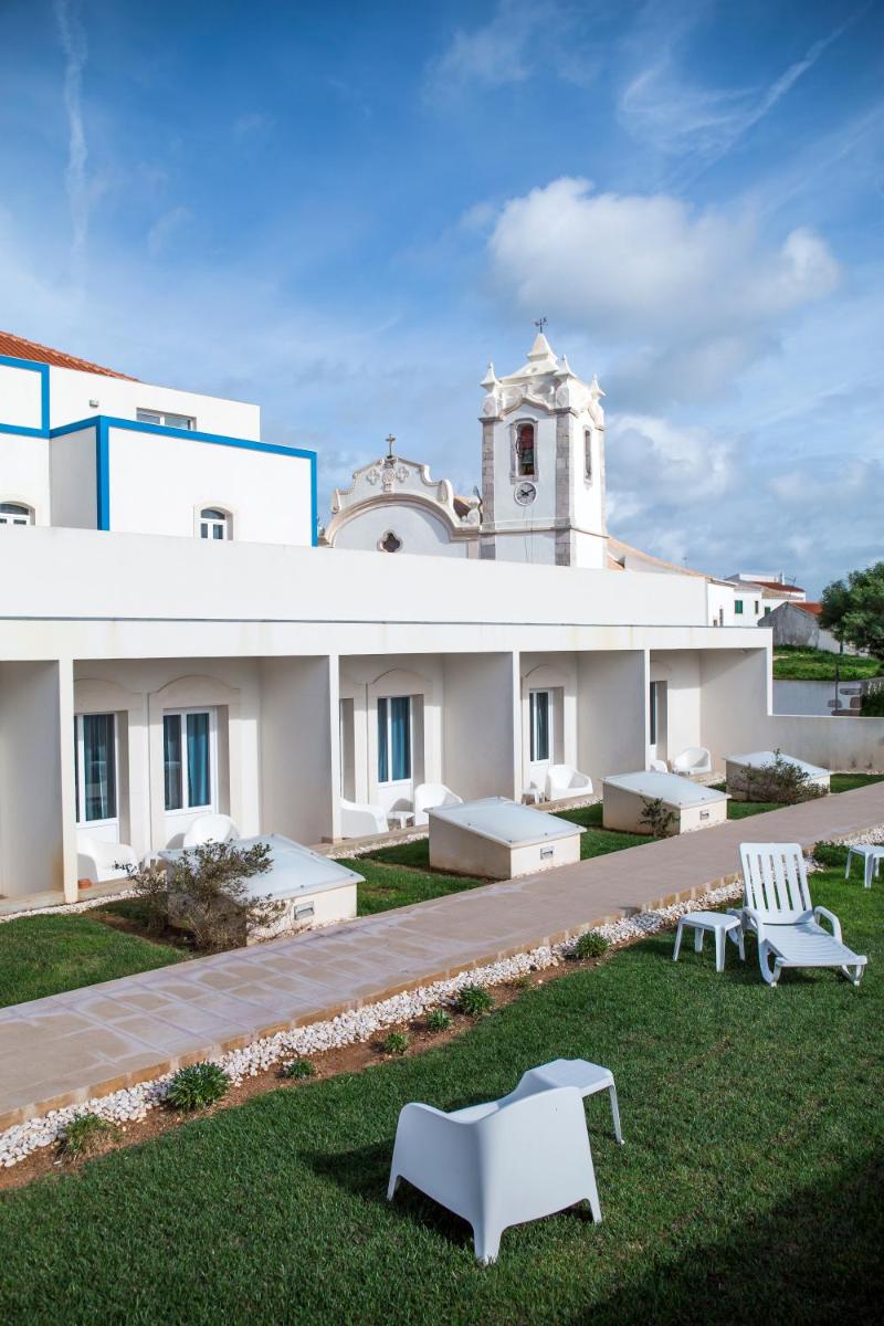 um edifício com dois bancos brancos na relva em Hotel Mira Sagres em Vila do Bispo