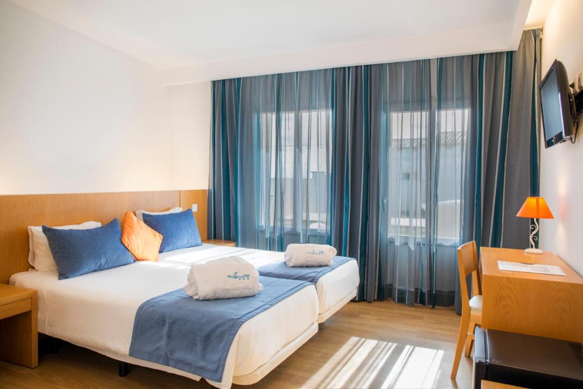 um quarto com duas camas com travesseiros azuis em Hotel Mira Sagres em Vila do Bispo mais 32 fotografias