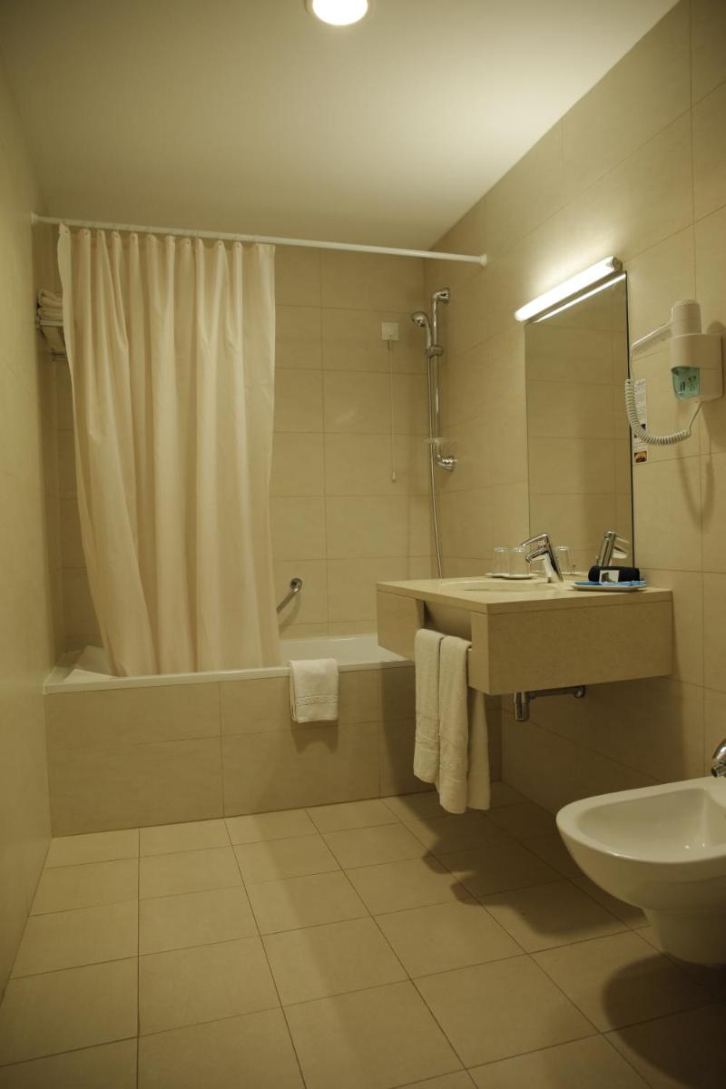 um banheiro com banheira, pia e chuveiro em Hotel Mira Sagres em Vila do Bispo