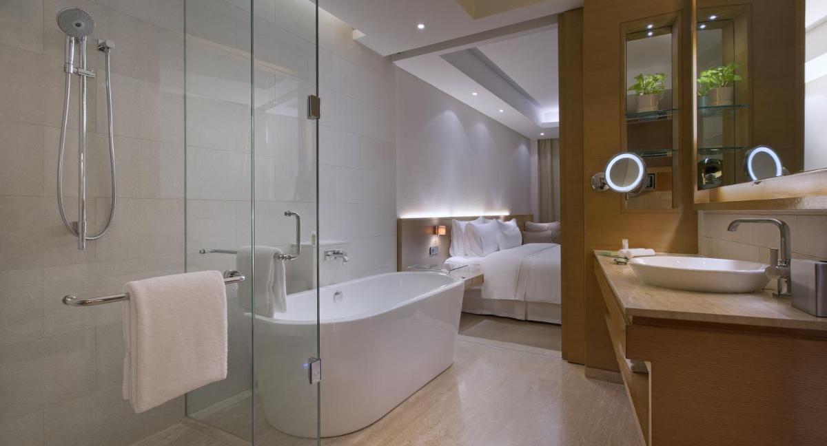 a bathroom with a tub and a shower and a sink at The Westin Mumbai Garden City in Mumbai