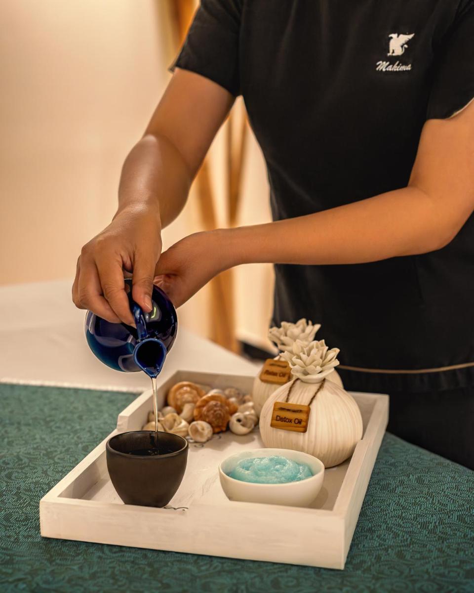 a person pouring liquid into a bowl on a table at JW Marriott Mumbai Juhu in Mumbai