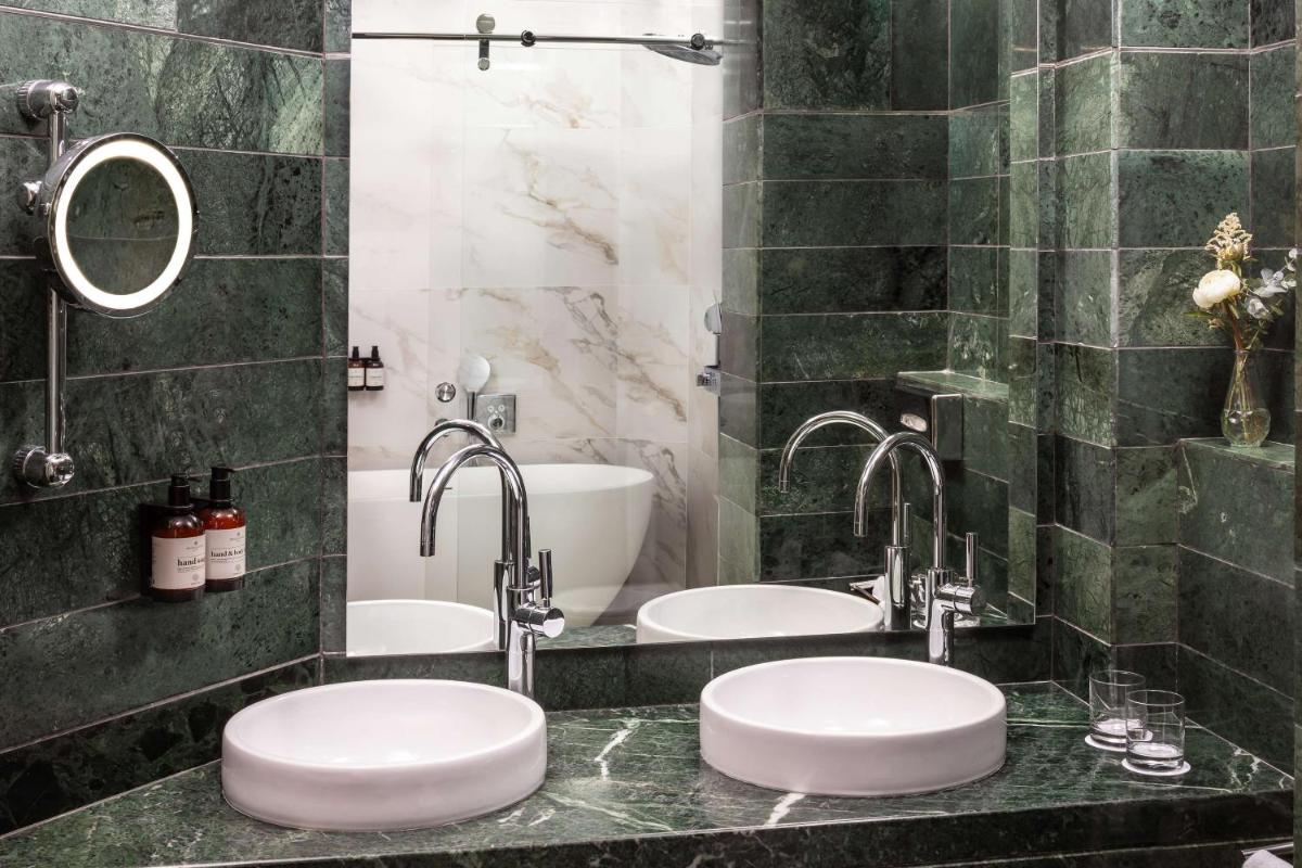 Dos lavabos en un baño con dos grifos en NH Collection Madrid Paseo del Prado, en Madrid