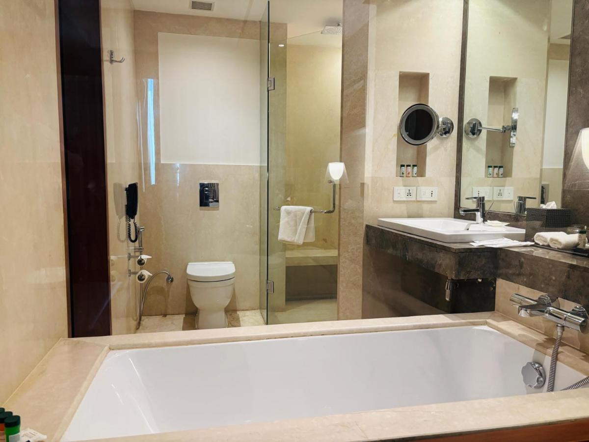 a bathroom with a tub and a toilet and a sink at The Anya Hotel-Golf Course Road in Gurgaon
