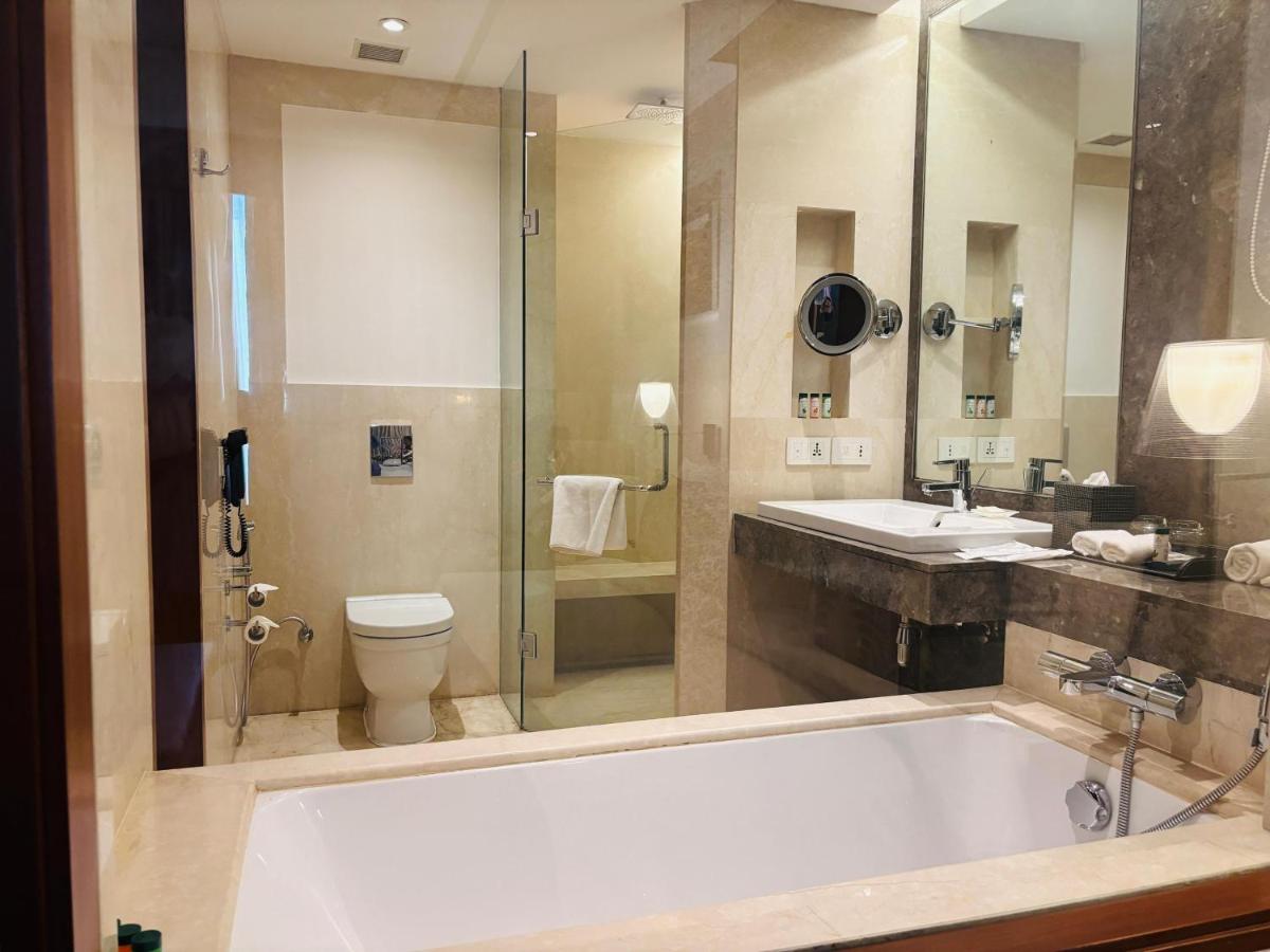 a bathroom with a tub and a sink and a toilet at The Anya Hotel-Golf Course Road in Gurgaon