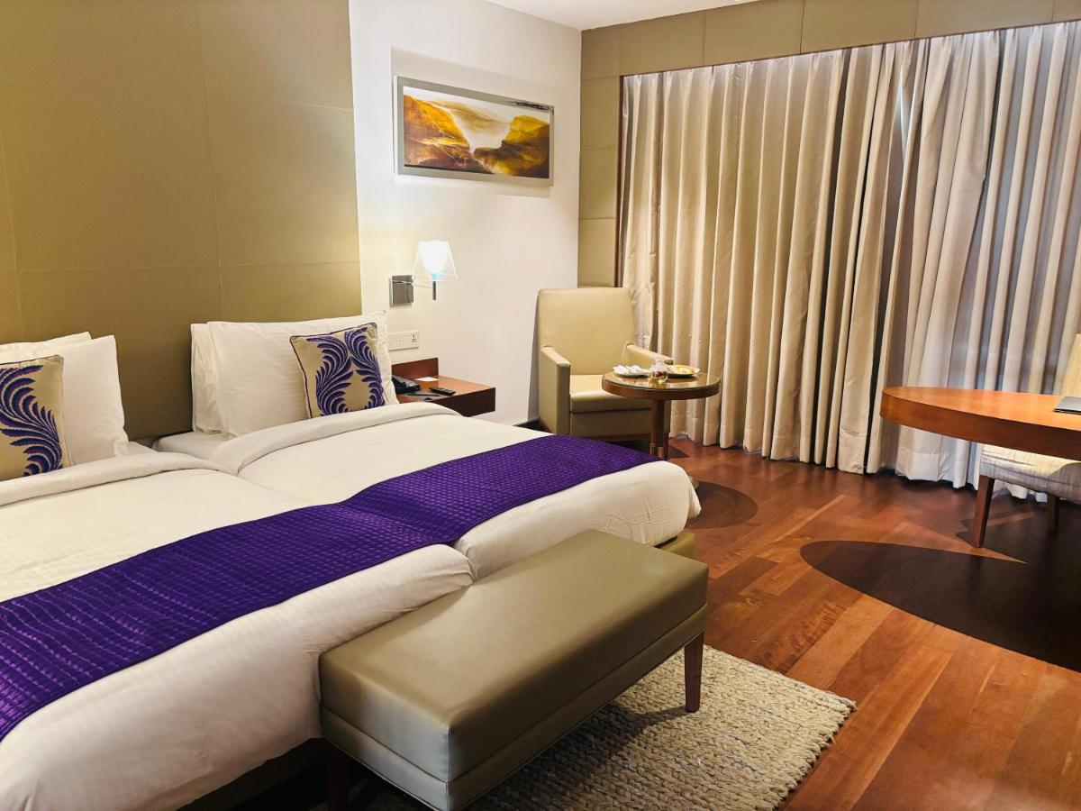 a hotel room with a large bed and a table at The Anya Hotel-Golf Course Road in Gurgaon