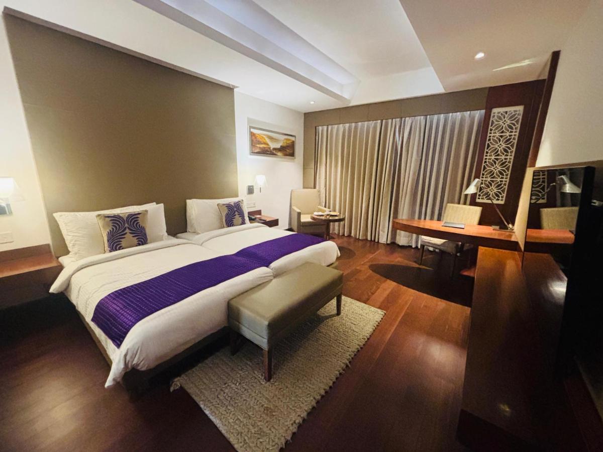 a bedroom with a large bed and a desk at The Anya Hotel-Golf Course Road in Gurgaon