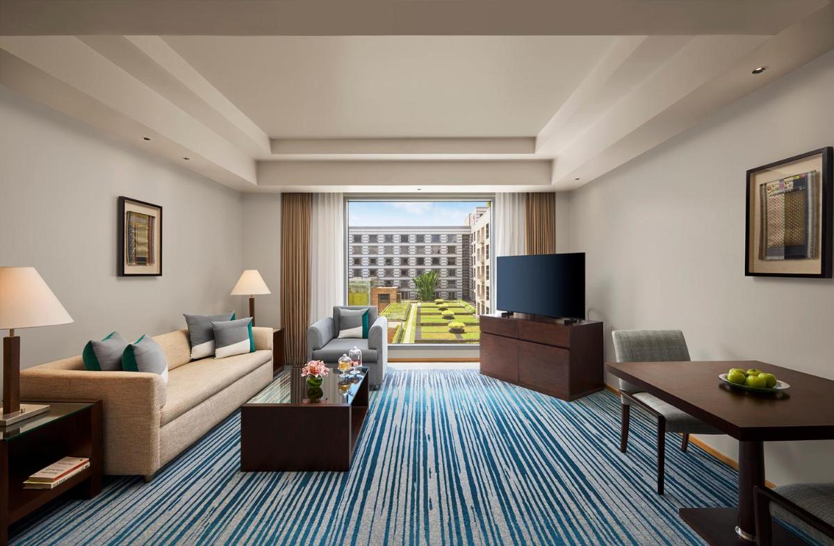 a living room with a couch and a tv at Grand Hyatt Mumbai Hotel and Residences in Mumbai