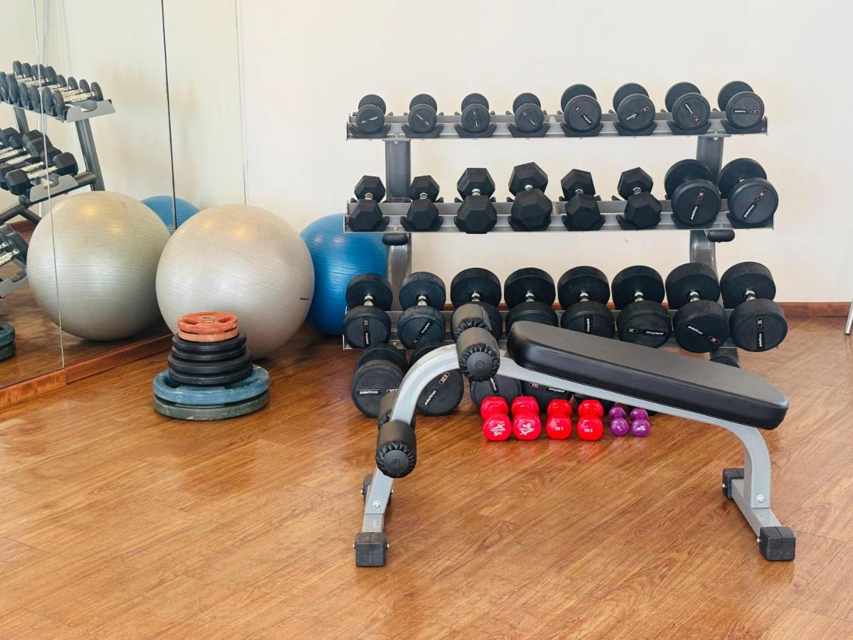 a gym with a rack of dumbbells and balls at The Anya Hotel-Golf Course Road in Gurgaon