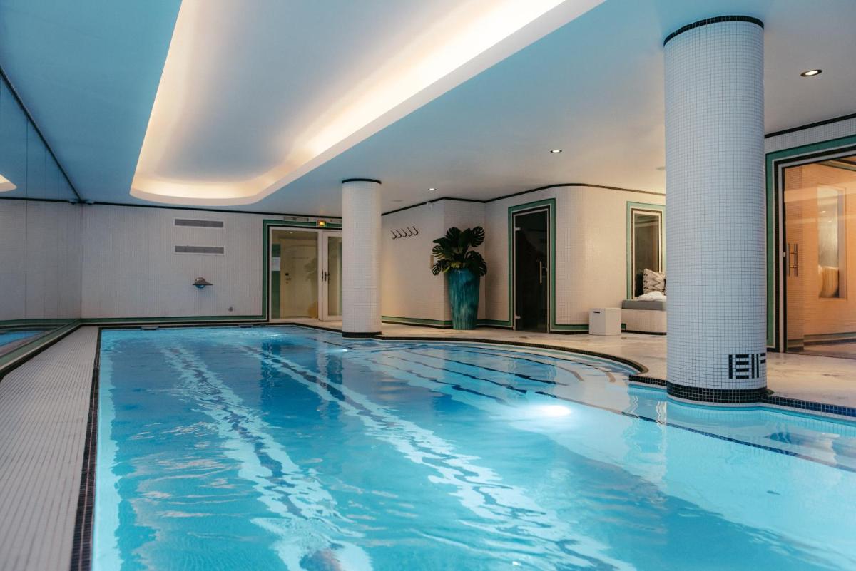 une grande piscine avec de l'eau bleue dans un immeuble dans l'établissement Hotel Eiffel Blomet, à Paris