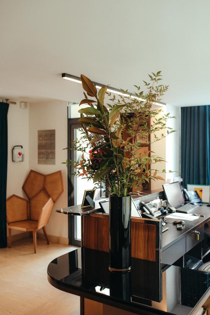un bureau avec un vase avec une plante sur un bureau dans l'établissement Hotel Eiffel Blomet, à Paris