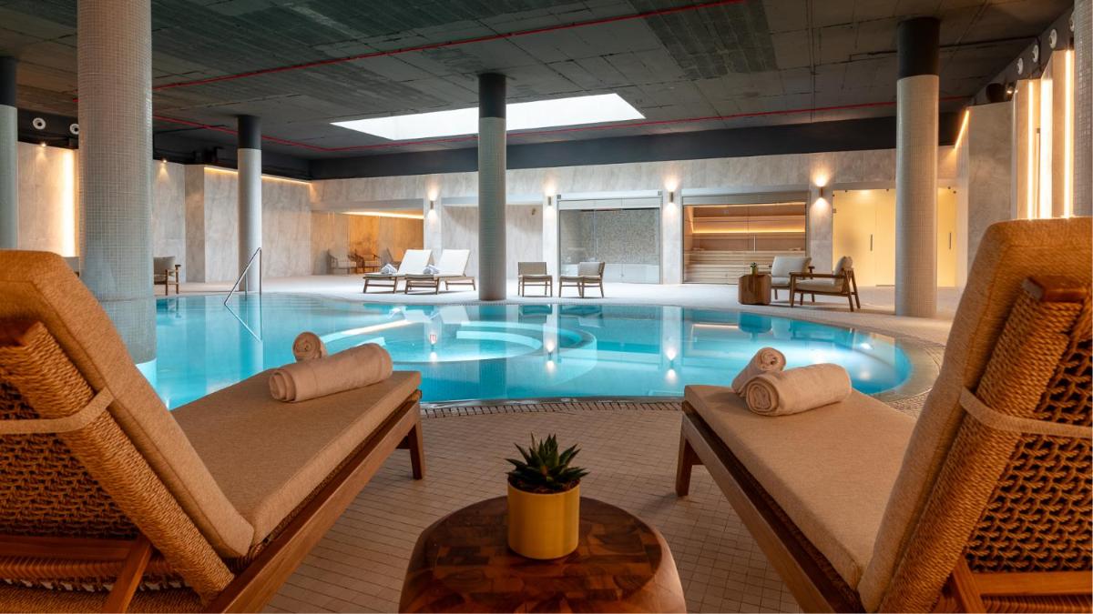 una gran piscina en un hotel con 2 sillas y una mesa en Hiru Uhinak, en Deba