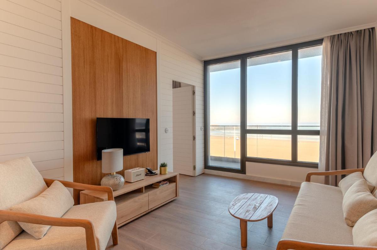 Una sala de estar con un sofá y un televisor. en Hiru Uhinak, en Deba