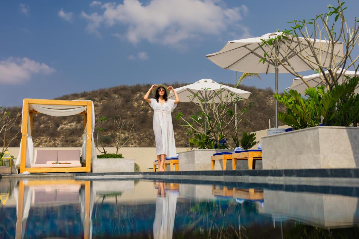 a woman in a white dress standing next to a swimming pool at Taj Amer, Jaipur in Jaipur