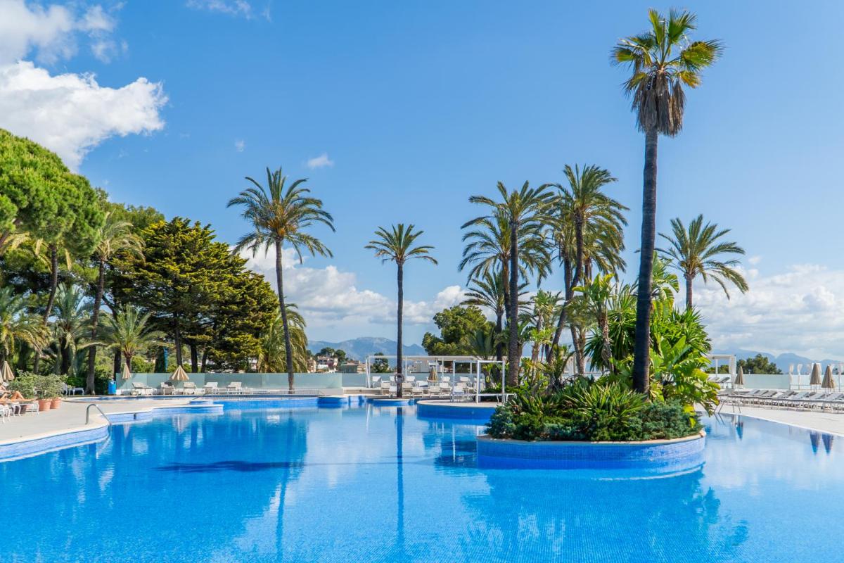 Una gran piscina con palmeras en un complejo turístico. en GPRO Valparaiso Palace & Spa, en Palma de Mallorca