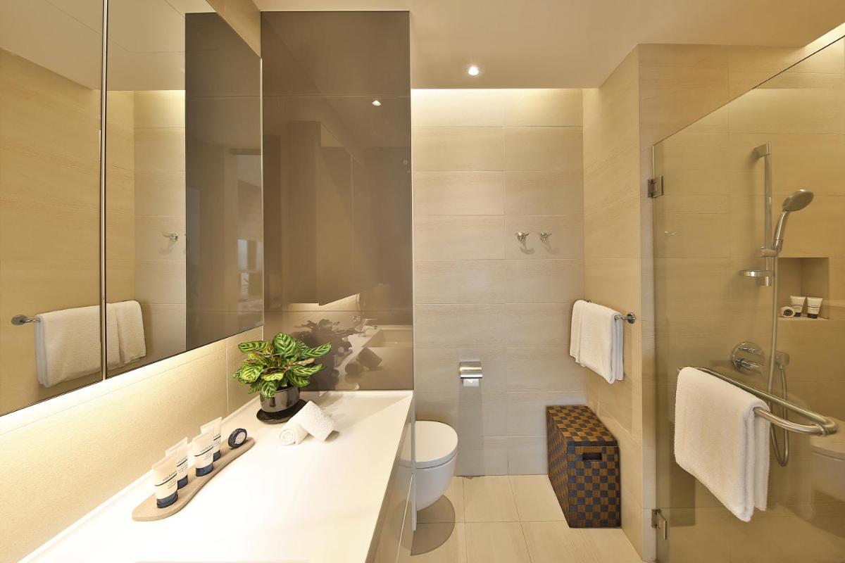 a bathroom with a sink and a toilet and a mirror at Pan Pacific Serviced Suites Beach Road, Singapore in Singapore