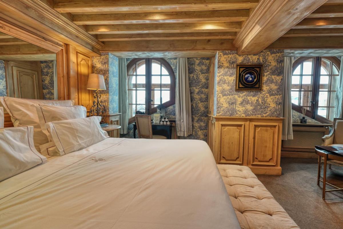 une chambre avec un grand lit dans une pièce dans l'établissement Le Saint Joseph, à Courchevel