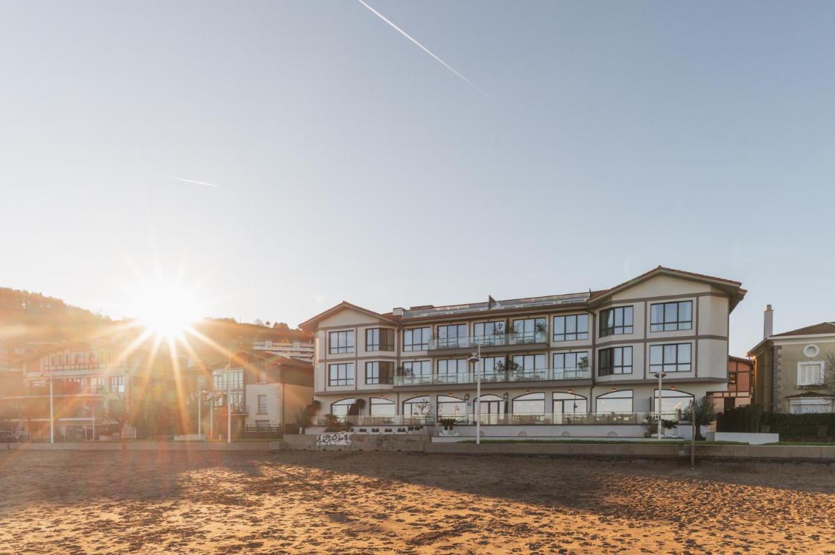 un edificio en la playa con el sol al fondo en Hiru Uhinak, en Deba