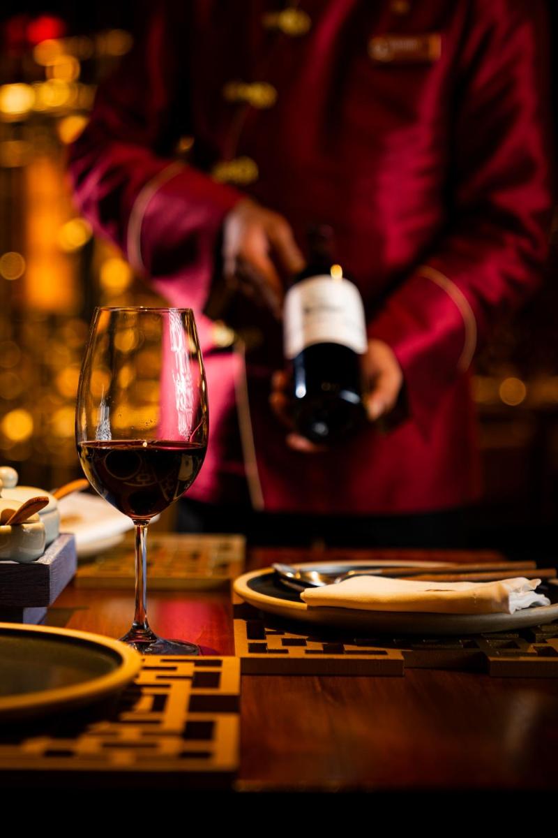 a person pouring a glass of wine on a table at President - IHCL SeleQtions in Mumbai