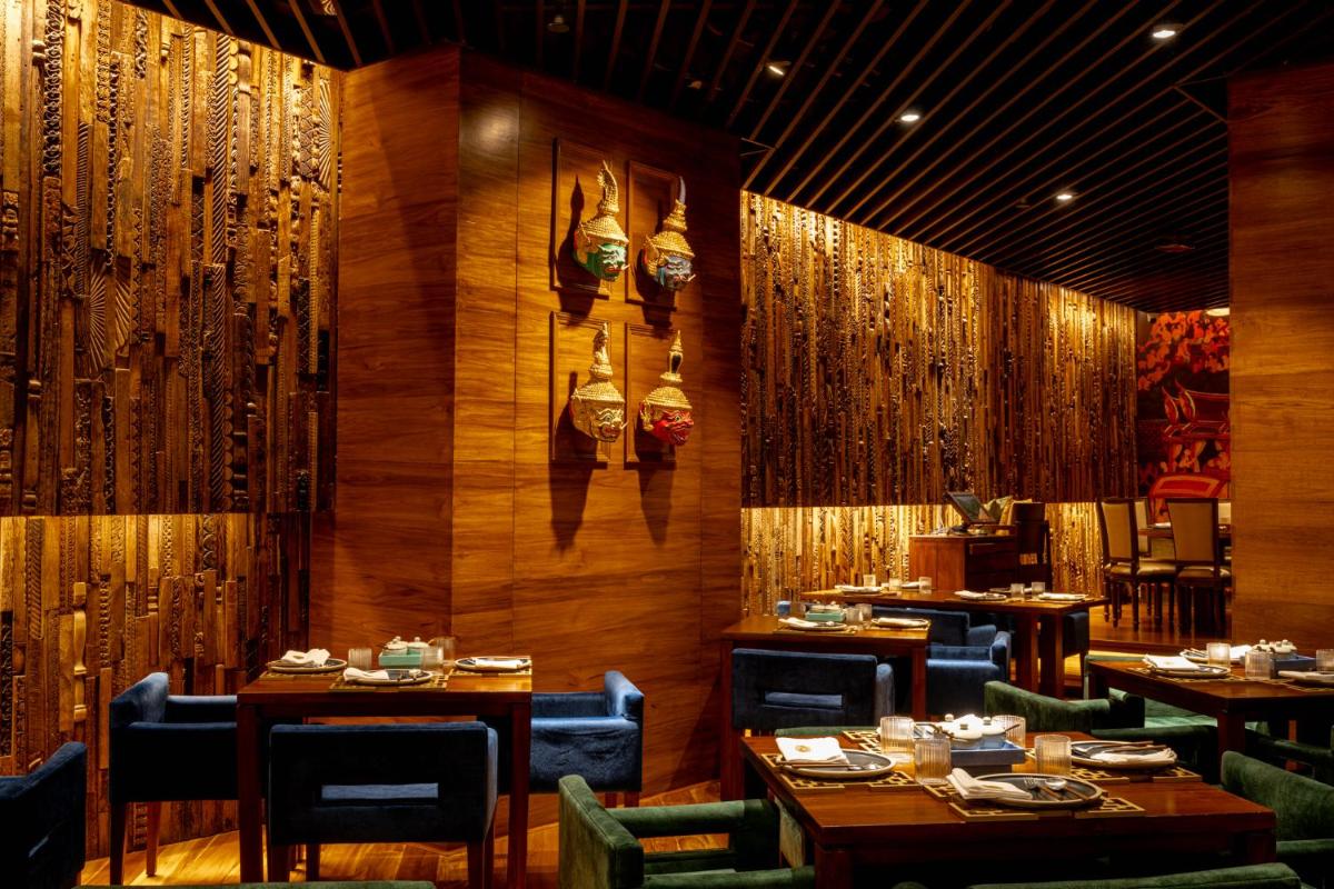 a restaurant with wooden walls and tables and chairs at President - IHCL SeleQtions in Mumbai