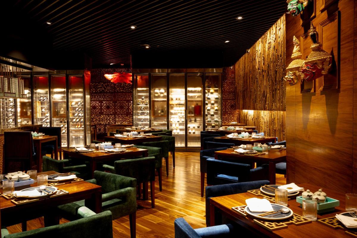 a restaurant with wooden tables and chairs in a room at President - IHCL SeleQtions in Mumbai