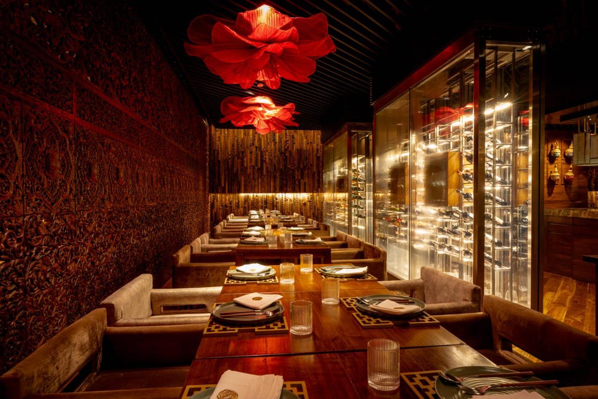 a row of tables in a restaurant with a chandelier at President - IHCL SeleQtions in Mumbai