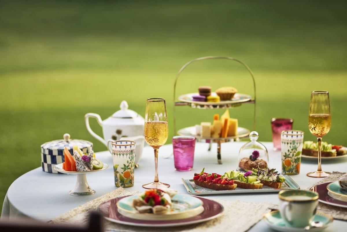 a table with plates of food and glasses of wine at Jai Mahal Palace in Jaipur
