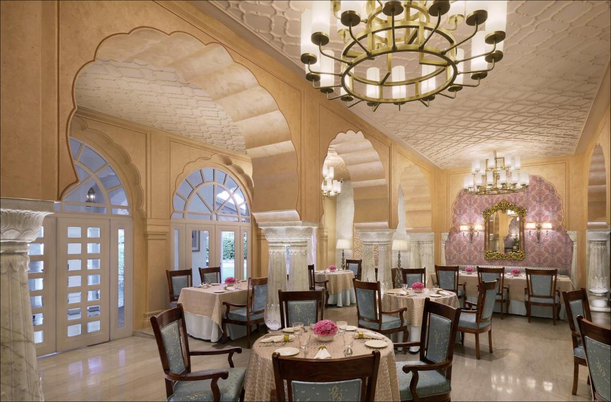 a dining room with tables and chairs and a chandelier at Jai Mahal Palace in Jaipur