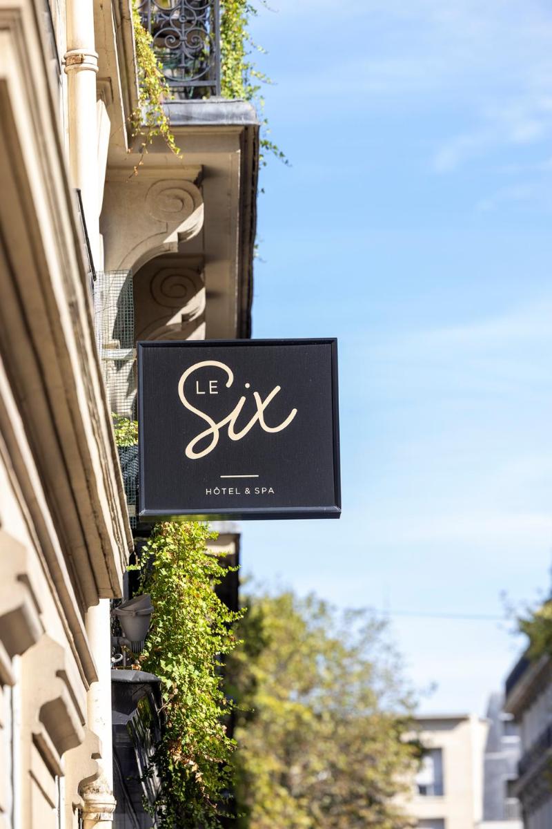un panneau indiquant un magasin sur le côté d'un bâtiment dans l'établissement Hotel Le Six, à Paris